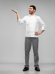 Image showing happy smiling male chef holding something on hand