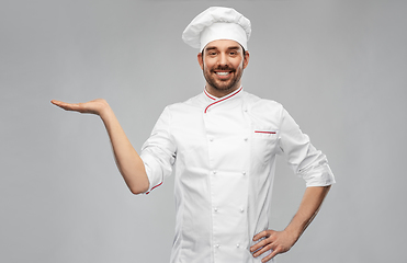 Image showing happy smiling male chef holding something on hand