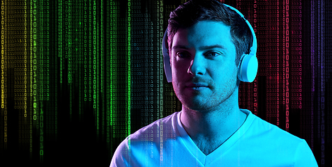 Image showing man in headphones over neon lights and binary code