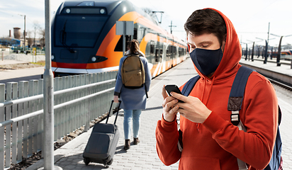 Image showing man in mask with smartphone traveling by train