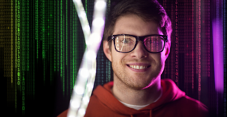 Image showing man in glasses over neon lights and binary code