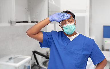 Image showing tired indian male doctor in blue uniform and mask