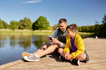 Image showing father and son with smartphone on river berth