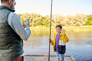 Image showing father photographing son with fishing rod on river