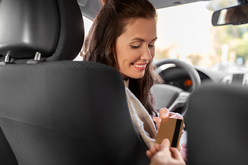 Image showing female car driver takes credit card from passenger