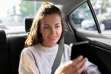 Image showing smiling woman using smartphone in taxi car