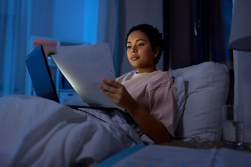 Image showing woman with laptop and papers in bed at night