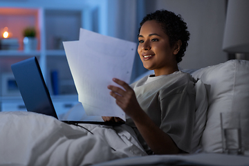 Image showing woman with laptop and papers in bed at night