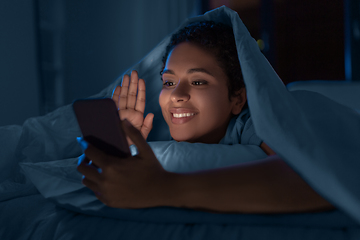 Image showing woman with phone having video call in bed at night