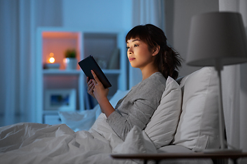 Image showing asian woman with tablet pc in bed at home at night