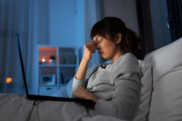 Image showing stressed woman with laptop working in bed at night