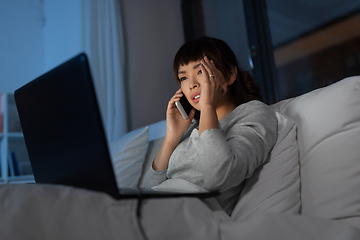 Image showing woman with laptop calling on phone in bed at night