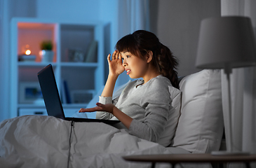 Image showing stressed woman with laptop working in bed at night