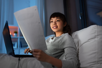 Image showing asian woman with laptop and papers in bed at night