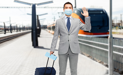 Image showing businessman in mask with travel bag over train