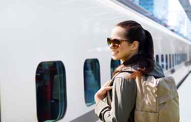 Image showing smiling woman with backpack traveling by train