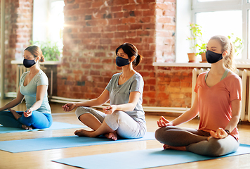 Image showing group of women in masks doing yoga at studio