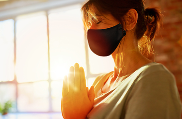 Image showing woman in black mask meditating at yoga studio