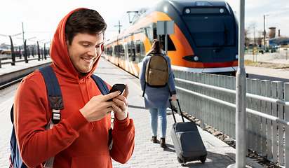 Image showing smiling man with smartphone traveling by train