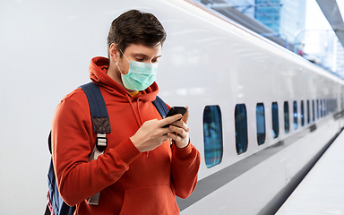 Image showing man in mask with smartphone traveling by train