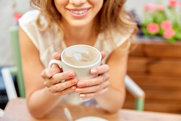 Image showing happy young woman drinking coffee at street cafe