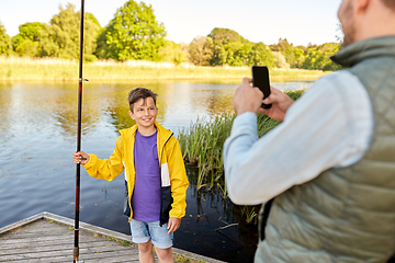 Image showing father photographing son with fishing rod on river