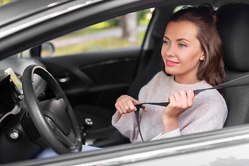 Image showing woman or female car driver fastening seat belt