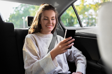 Image showing smiling woman using smartphone in taxi car