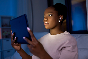 Image showing woman with tablet pc in earphones in bed at night