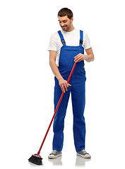 Image showing male cleaner in overall cleaning floor with broom