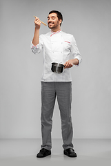 Image showing happy smiling male chef with saucepan tasting food