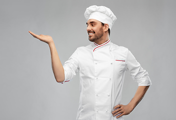 Image showing happy smiling male chef holding something on hand