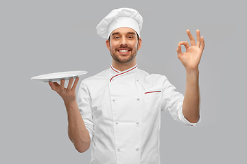 Image showing happy smiling male chef holding empty plate