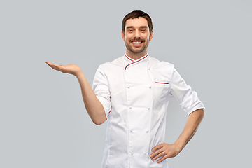 Image showing happy smiling male chef holding something on hand