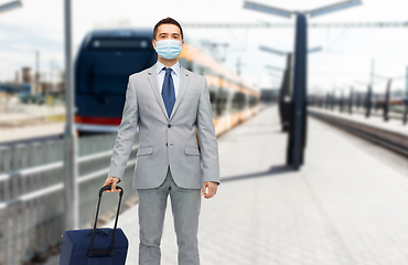 Image showing businessman in mask with travel bag over train