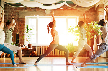 Image showing group of people doing yoga warrior pose at studio