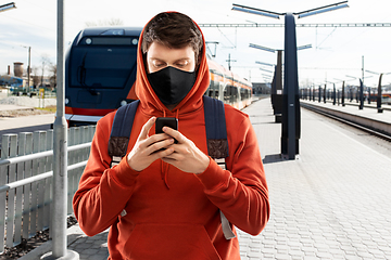 Image showing man in mask with smartphone traveling by train