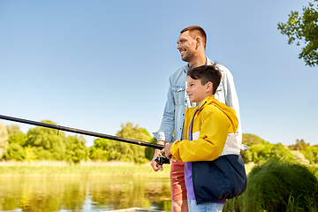 Image showing happy smiling father and son fishing on river