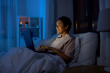 Image showing woman with laptop in bed at home at night