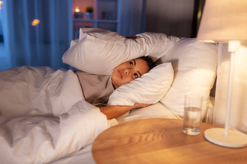 Image showing angry african woman lying in bed and closing ears