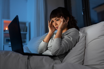 Image showing stressed woman with laptop working in bed at night