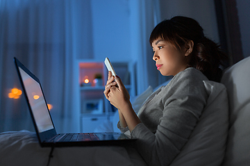 Image showing asian woman with smartphone in bed at night