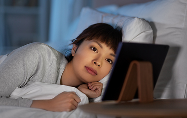 Image showing asian woman with tablet pc in bed at home at night