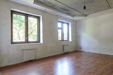 Image showing The interior of an empty room during renovation, there are two large windows in the room, heating radiators are located under the windows
