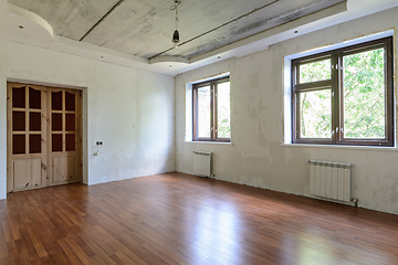 Image showing Interior of an empty room during renovation, view of a wall with windows and a wall with a door