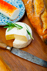 Image showing French cheese and fresh  baguette on a wood cutter