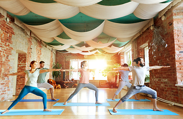 Image showing group of people doing yoga warrior pose at studio