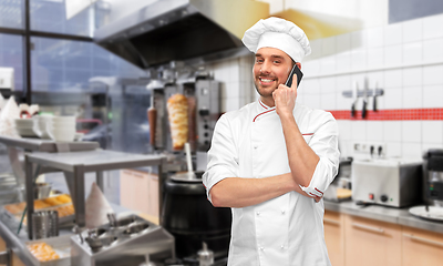 Image showing happy smiling male chef calling on smartphone