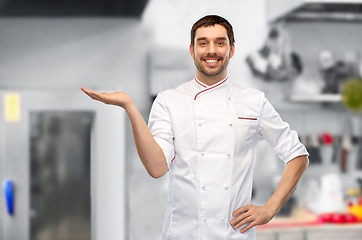 Image showing happy smiling male chef holding something on hand