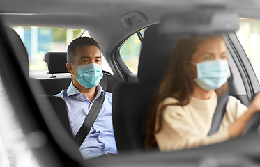 Image showing female driver in mask driving car with passenger